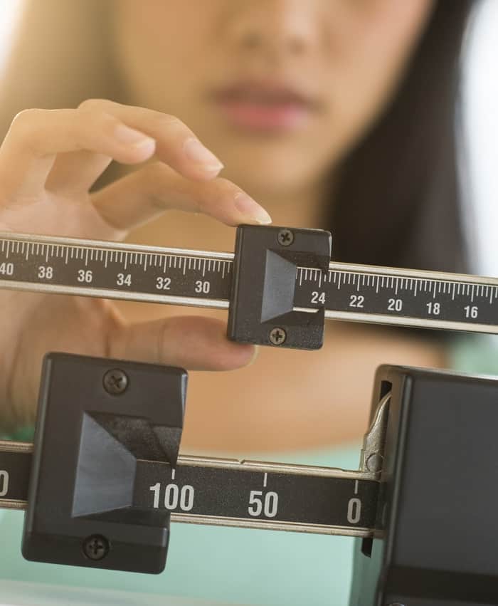 Midsection,Of,Mid,Adult,Asian,Woman,Adjusting,Balance,Weight,Scale