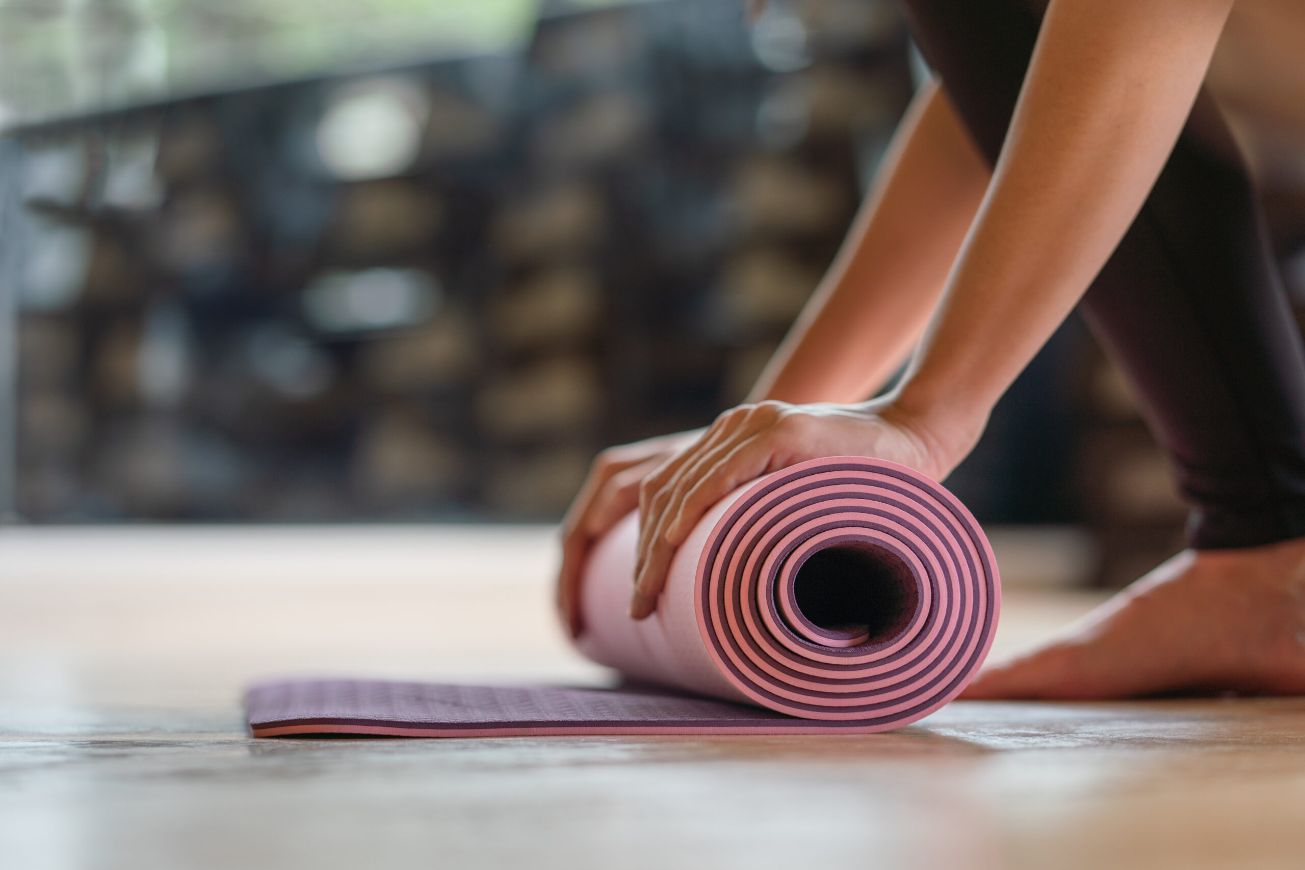 Kansas Built Fitness | Mind & Body classes featuring Yoga and Pilates in Olathe, KS | Pink yoga mat being rolled up by hands